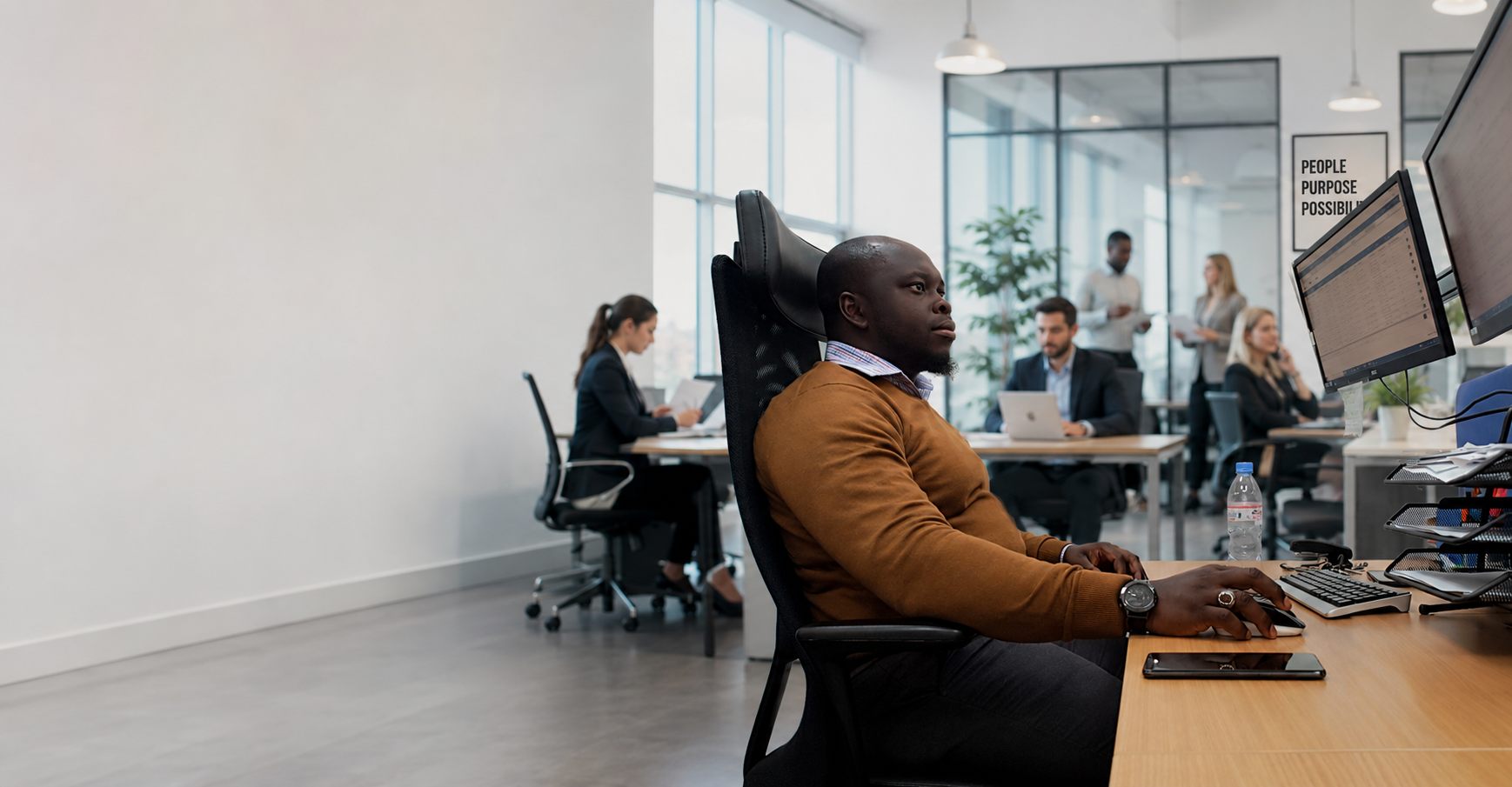 A recruitment consultant working at a desk in a busy office